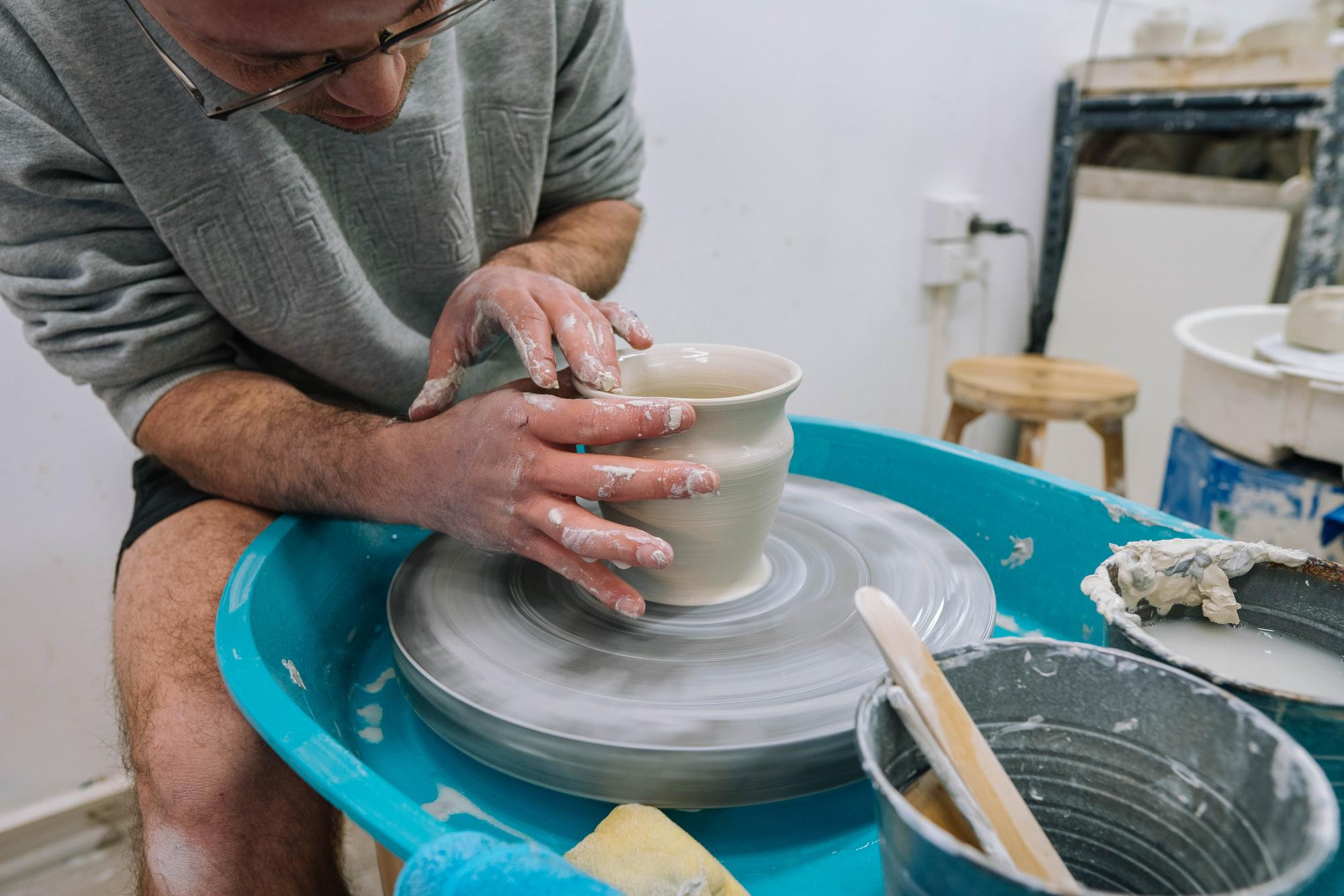 A man making a pot while wheel throwing.